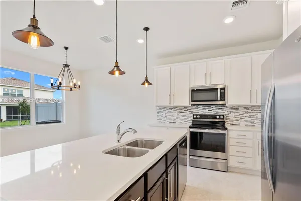a kitchen with stainless steel appliances a stove a sink a refrigerator and a counter space