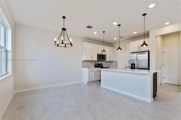 a kitchen with kitchen island white cabinets and refrigerator