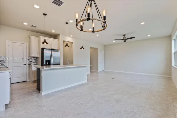 a large kitchen with cabinets a sink stainless steel appliances and a chandelier
