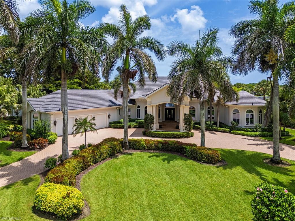 a view of a house with a yard and palm trees