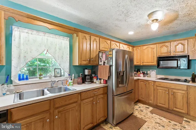 a kitchen with a refrigerator a sink stainless steel appliances cabinets and a large window