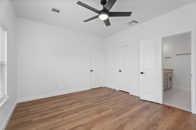 an empty room with wooden floor a ceiling fan and closet