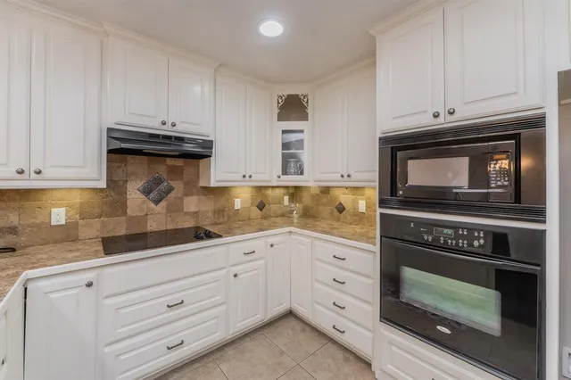 a kitchen with granite countertop white cabinets and stainless steel appliances