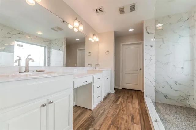 a spacious bathroom with a granite countertop sink a mirror and a shower
