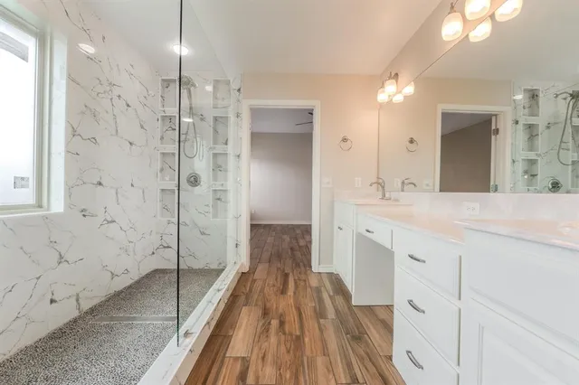 a spacious bathroom with a double vanity sink a large mirror and shower