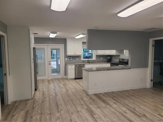 a large kitchen with cabinets wooden floor and stainless steel appliances