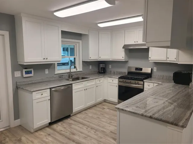a kitchen with granite countertop white cabinets and appliances