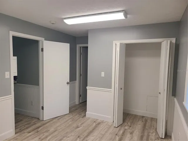 a view of an empty room with closet and wooden floor