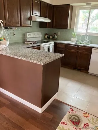 a kitchen with granite countertop a sink a stove and wooden cabinets