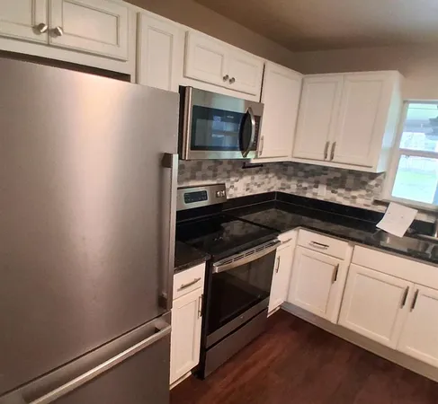 a kitchen with granite countertop white cabinets and black appliances