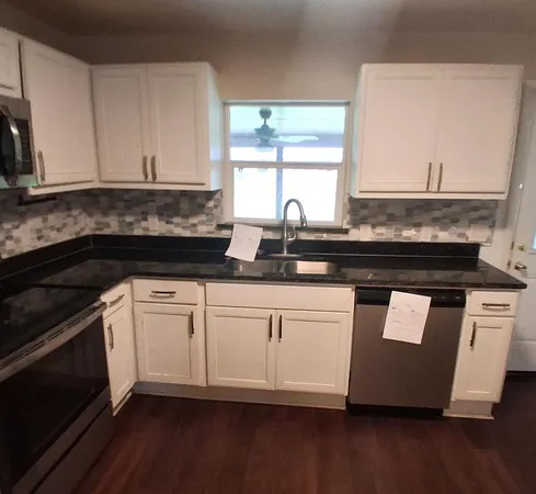 a kitchen with granite countertop white cabinets and black appliances