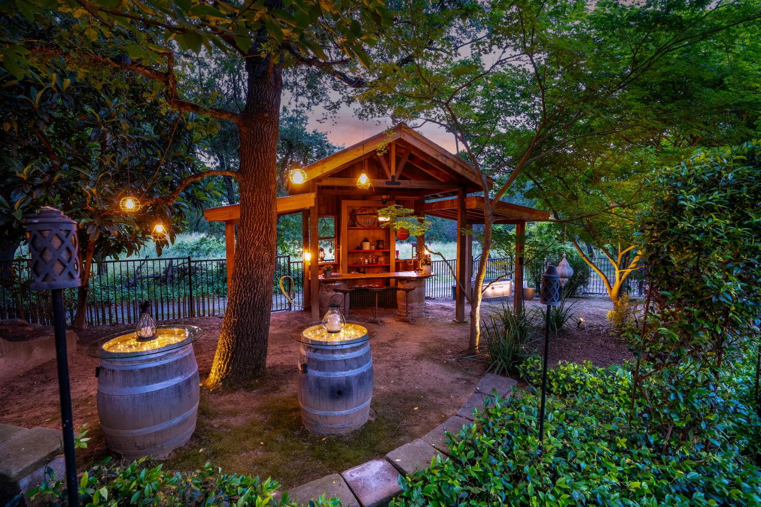6533 Landis Avenue Carmichael, CA 95608 - Photo 11 of 77 Tucked into the backyard, this outdoor whiskey bar feels like a hidden retreat with playful charm. Warm wood tones and carefully arranged wine barrels set the stage. Overhead strings of lights keep the atmosphere whimsy and magical. It is a space designed to draw people in. Whether you’re hosting a lively celebration or a relaxed evening gathering, the bar effortlessly becomes the heart of the event.