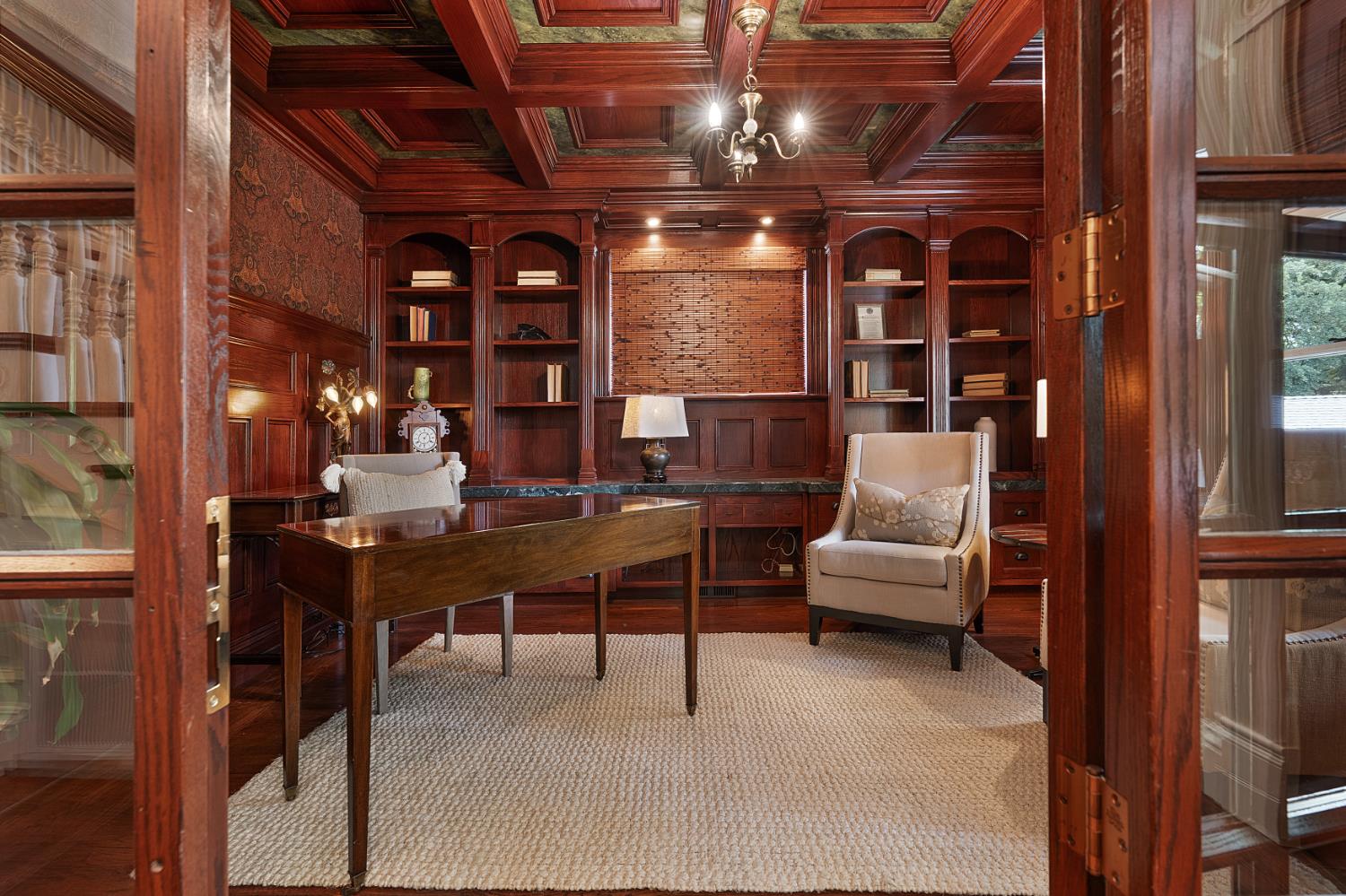 6533 Landis Avenue Carmichael, CA 95608 - Photo 21 of 77 This refined front office features glass-paneled French doors, rich hardwood flooring, and a White Oak box-beamed ceiling finished in mahogany stain, accented by faux-painted Italian marble inlays. Custom built-ins, Ralph Lauren wallpaper, a walk-in closet, and abundant windows combine to create a workspace that is both sophisticated and highly functional.