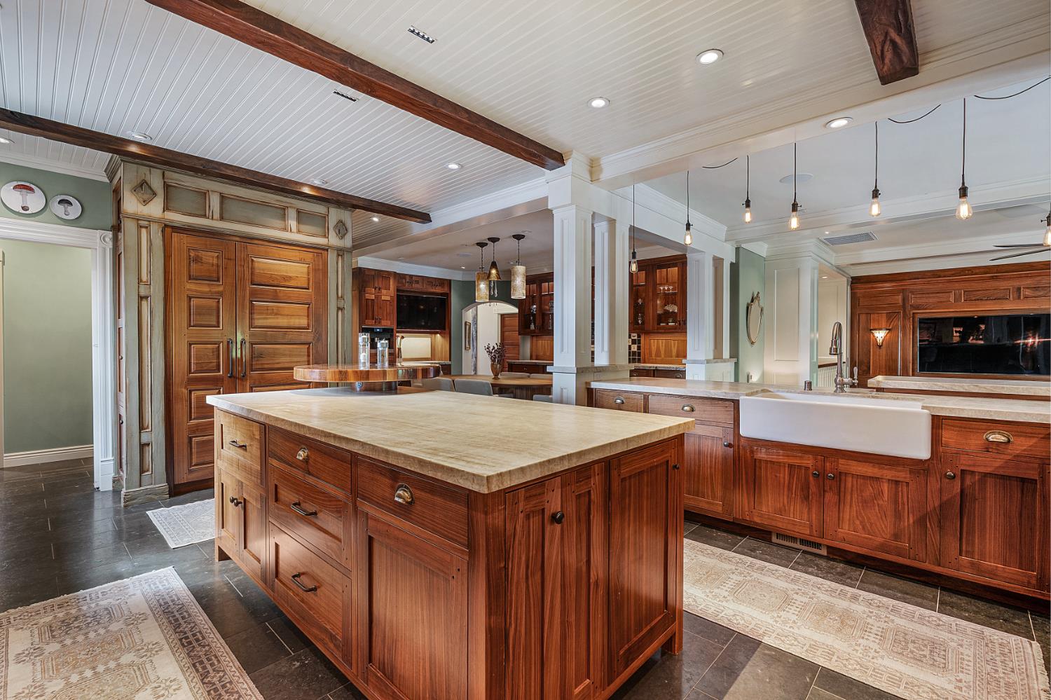 6533 Landis Avenue Carmichael, CA 95608 - Photo 25 of 77 The kitchen is framed by exquisite custom walnut cabinetry crafted by Puente Construction, paired with striking leathered Taj Mahal quartzite countertops that exude natural elegance. Thoughtful design continues with integrated lighting, pull-out storage, and specialized organization systems throughout. Completing the kitchen are two classic farmhouse sinks by Shaws. a spacious pantry with custom pull-outs, dual trash and recycling centers, and dedicated water filtration systems for both the refrigerator and espresso machine, delivering a seamless blend of beauty, innovation, and enduring craftsmanship.