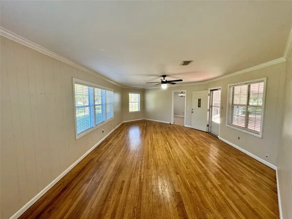 a view of empty room with wooden floor and fan