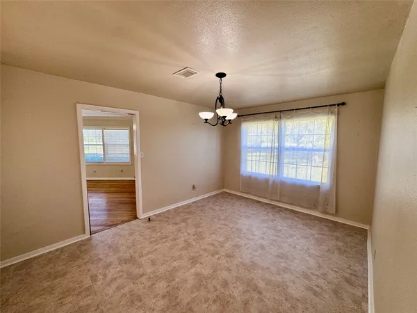 an empty room with chandelier fan and windows