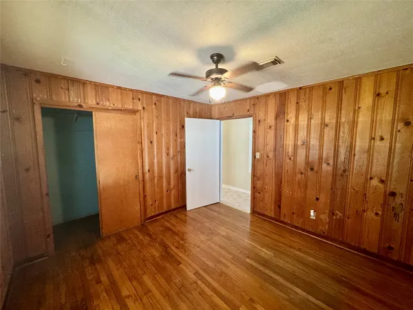 an empty room with wooden floor fan and windows