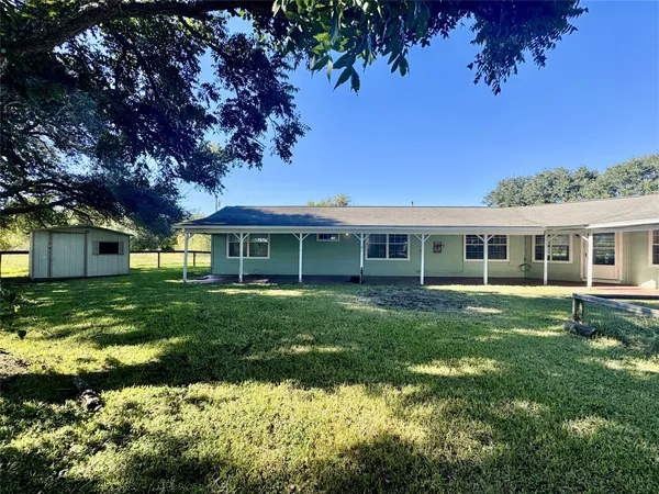 a view of a house with a big yard and potted plants and large trees