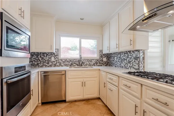 a kitchen with white cabinets sink and appliances