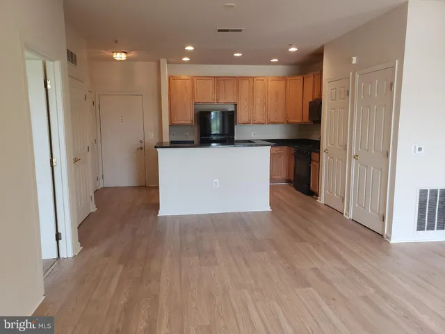 a view of kitchen with kitchen island granite countertop wooden floor and stainless steel appliances