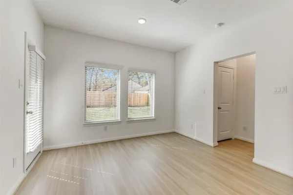 a view of an empty room with wooden floor and a window