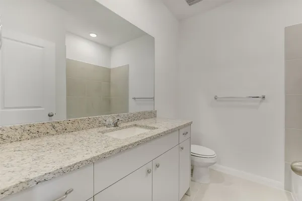 a bathroom with a granite countertop sink a toilet and a mirror