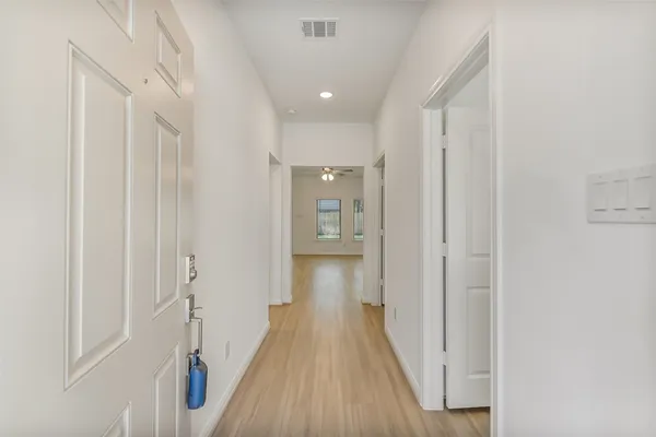 a view of a hallway with wooden floor and a bathroom