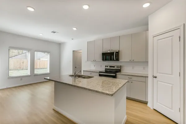a kitchen with granite countertop a stove a sink and a refrigerator