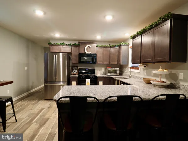 a kitchen with granite countertop a stove top oven cabinetry a sink and a microwave