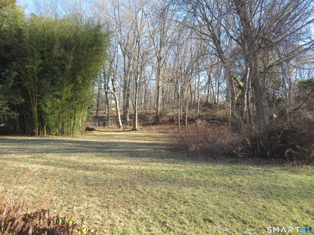a backyard of a house with large trees and outdoor seating