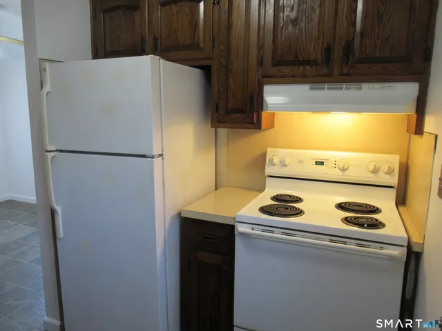 a white refrigerator freezer and a stove sitting inside of a kitchen