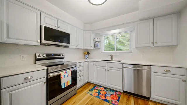 a kitchen with stainless steel appliances white cabinets granite counter tops and a window
