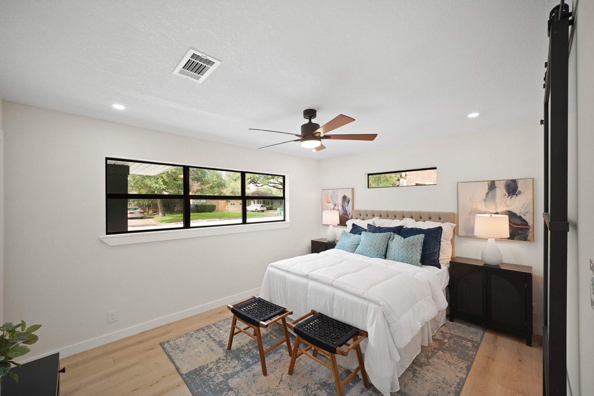 4813 Hummingbird Street Houston, TX 77035 - Photo 13 of 50 The Primary Bedroom (North Wing) features Wide Plank White Oak Hued Engineered Floors, Contemporary Style Onyx Hued Ceiling Fan with Wood Blades and Light, and Side by Side Windows that view the Landscaped Front Yard.
