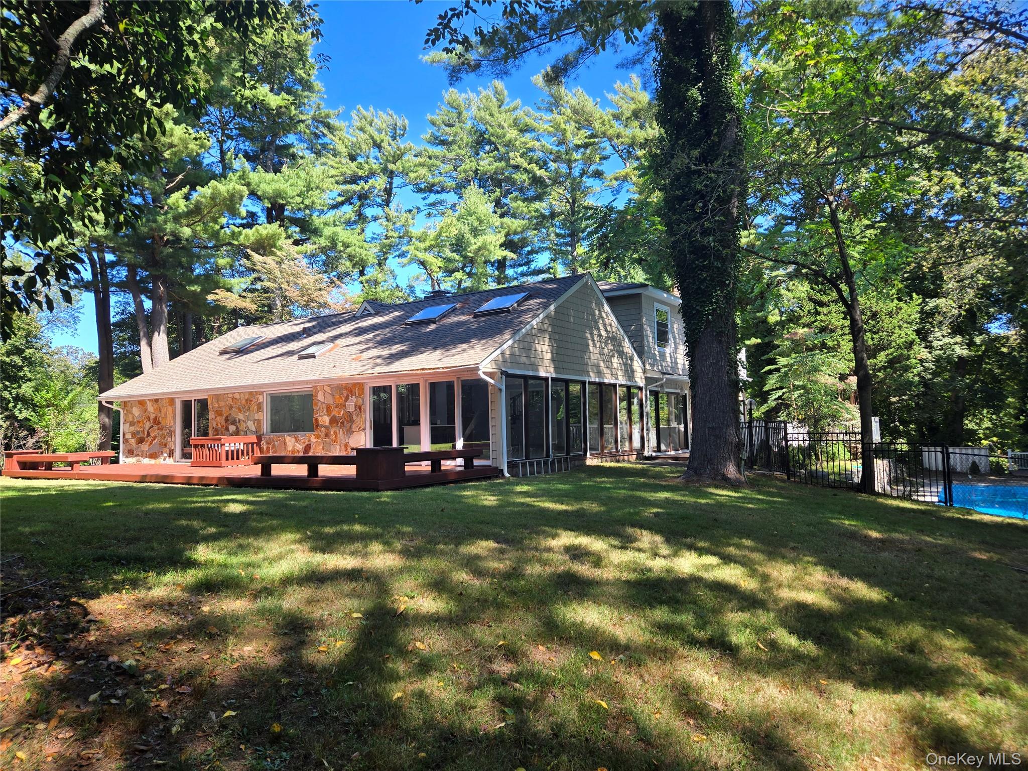 32 Valley Road Old Westbury, NY 11568 - Photo 8 of 45 Rear view of property featuring stone siding, a sunroom, and a deck