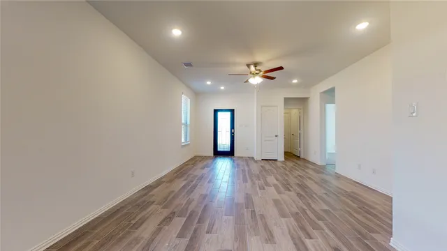 a view of a hallway with wooden floor and a window