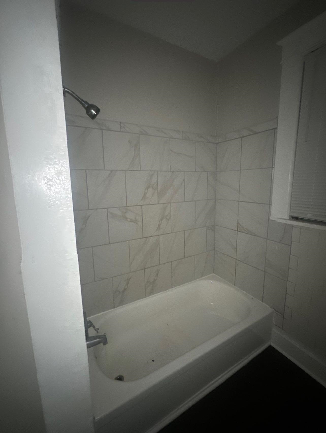 1165 Rayner Street Memphis, TN 38106 - Photo 7 of 16 White bathtub with chrome fixtures, surrounded by white tile with grey veining