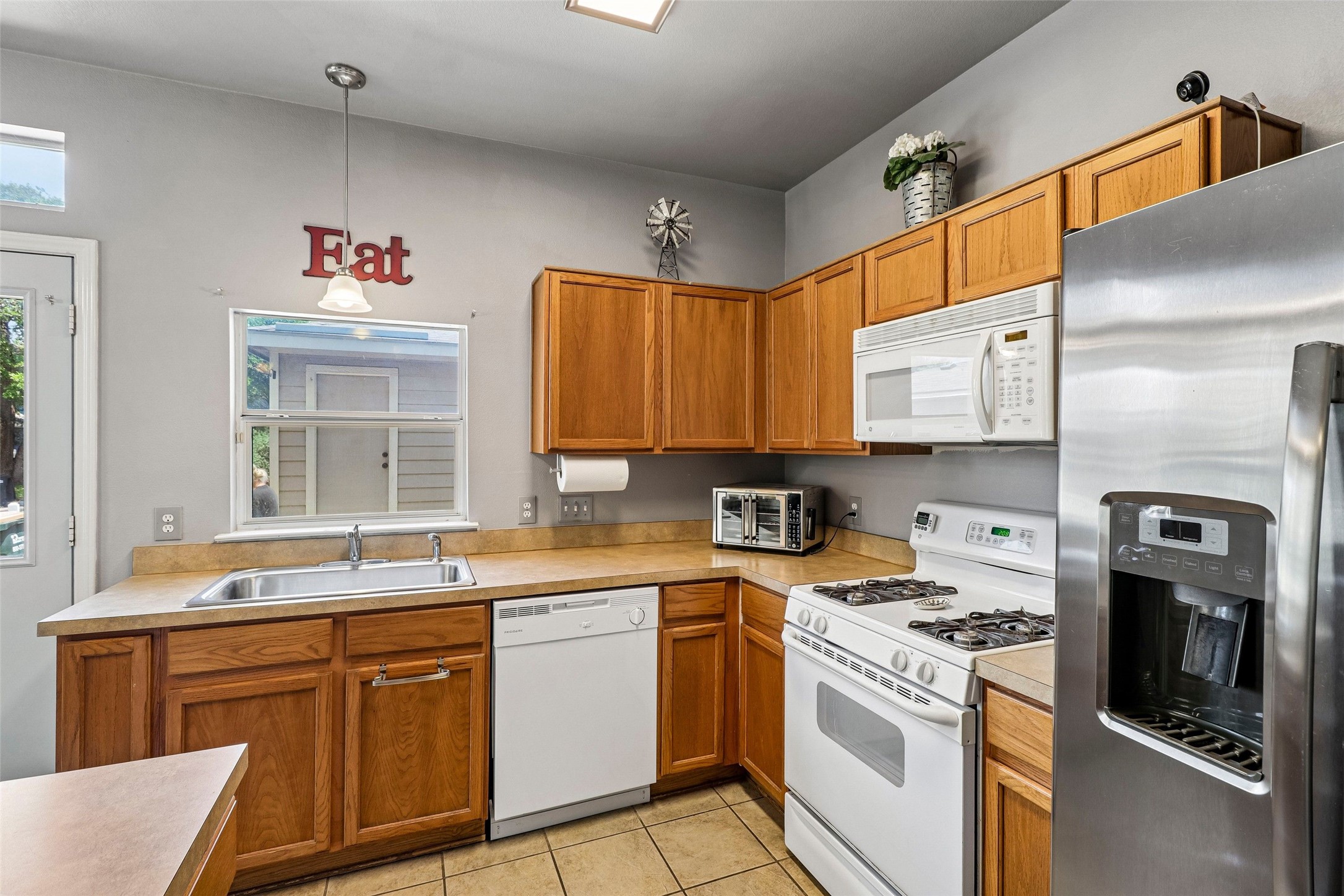 311 A Utterback Kyle, TX 78640 - Photo 13 of 40 Kitchen featuring wood-finish cabinetry, solid surface countertops, and tile flooring