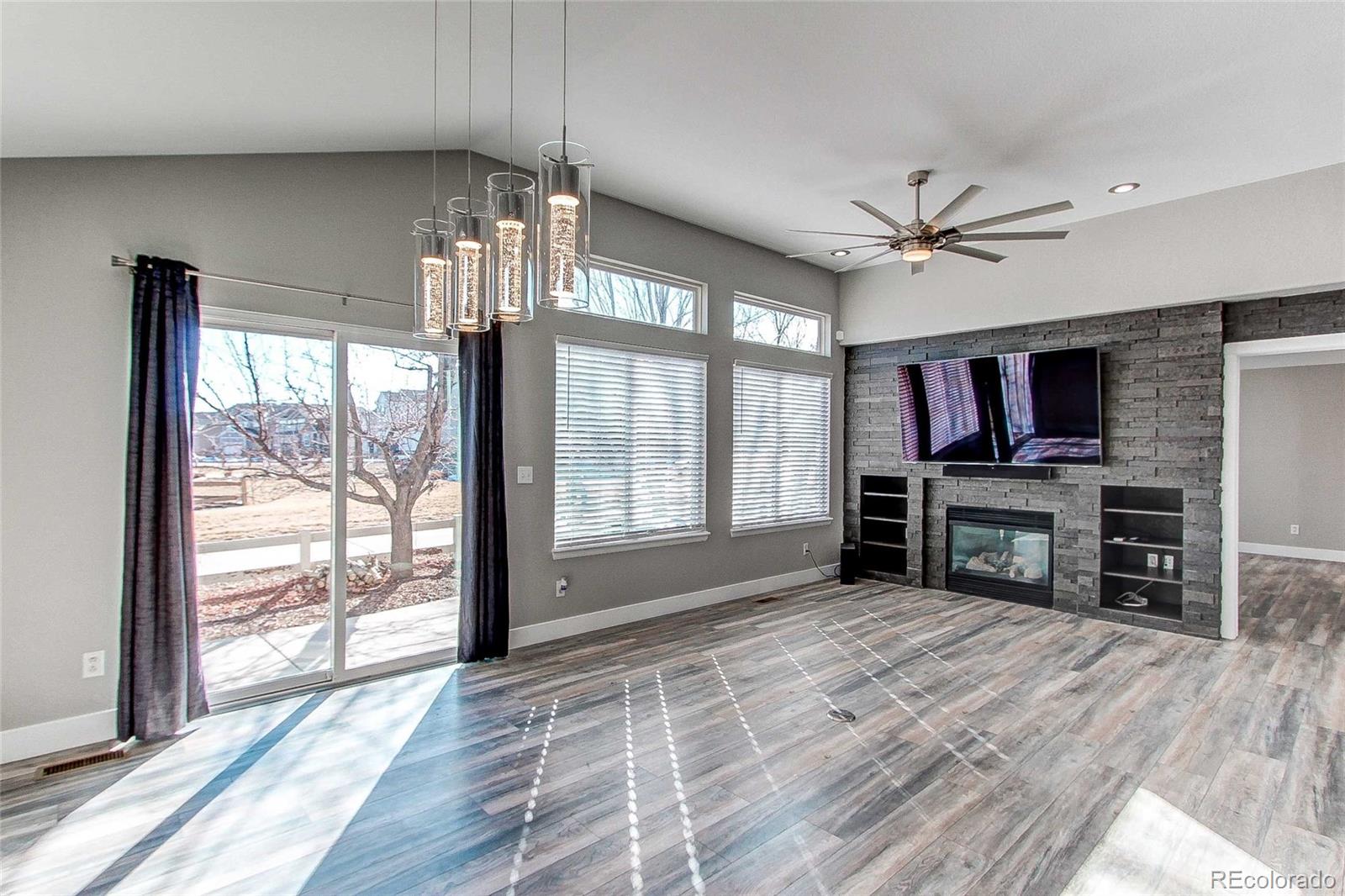 16082 Butterwort Circle Parker, CO 80134 - Photo 16 of 39 a view of a livingroom with a flat screen tv wooden floor and a ceiling fan
