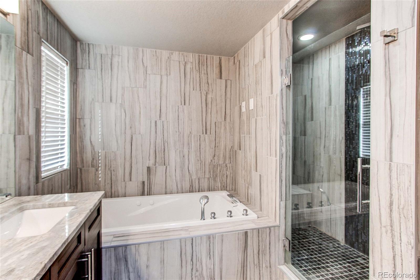16082 Butterwort Circle Parker, CO 80134 - Photo 23 of 39 a bathroom with a tub a sink and a shower
