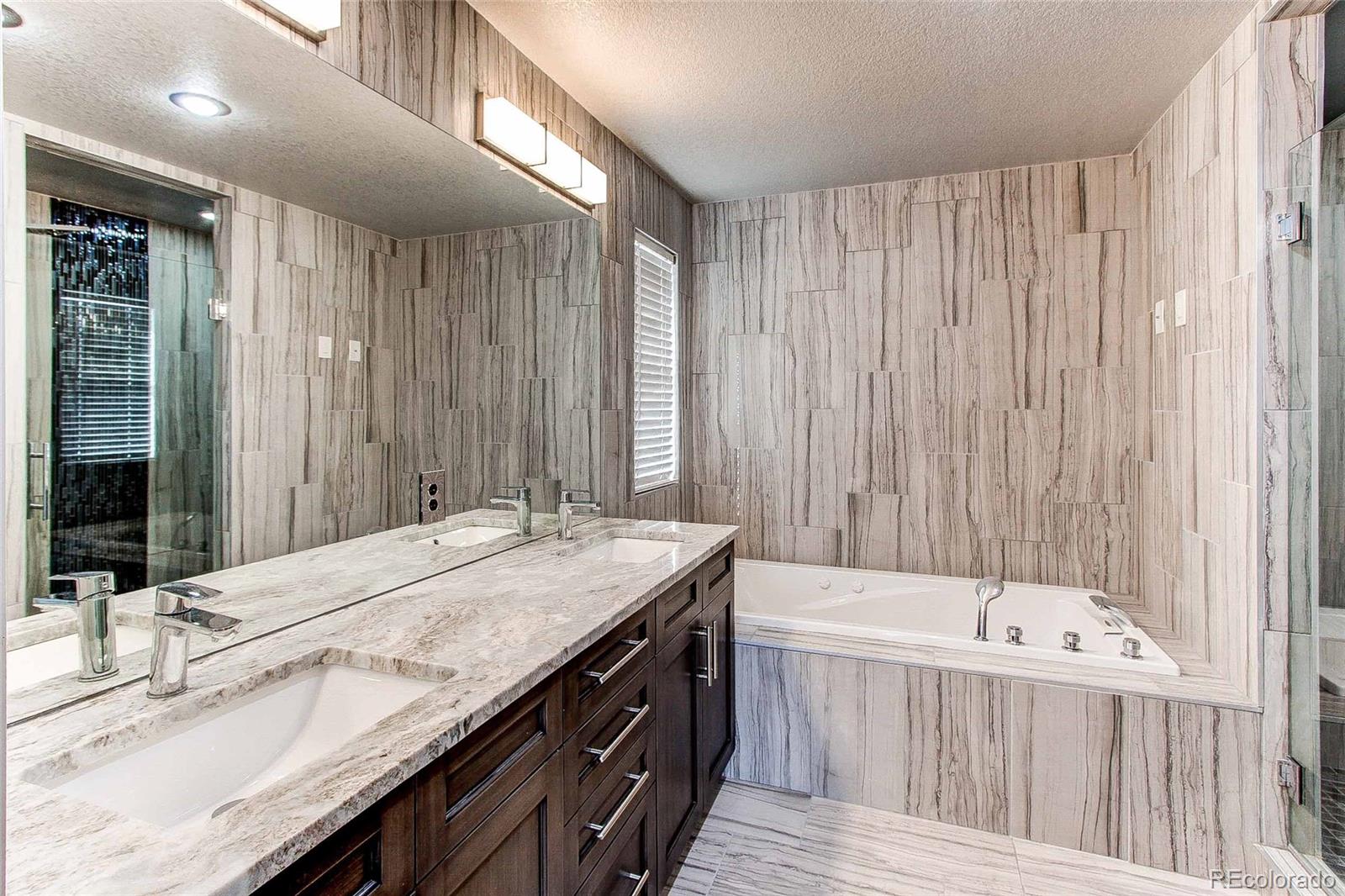 16082 Butterwort Circle Parker, CO 80134 - Photo 24 of 39 a bathroom with a granite countertop tub sink and mirror