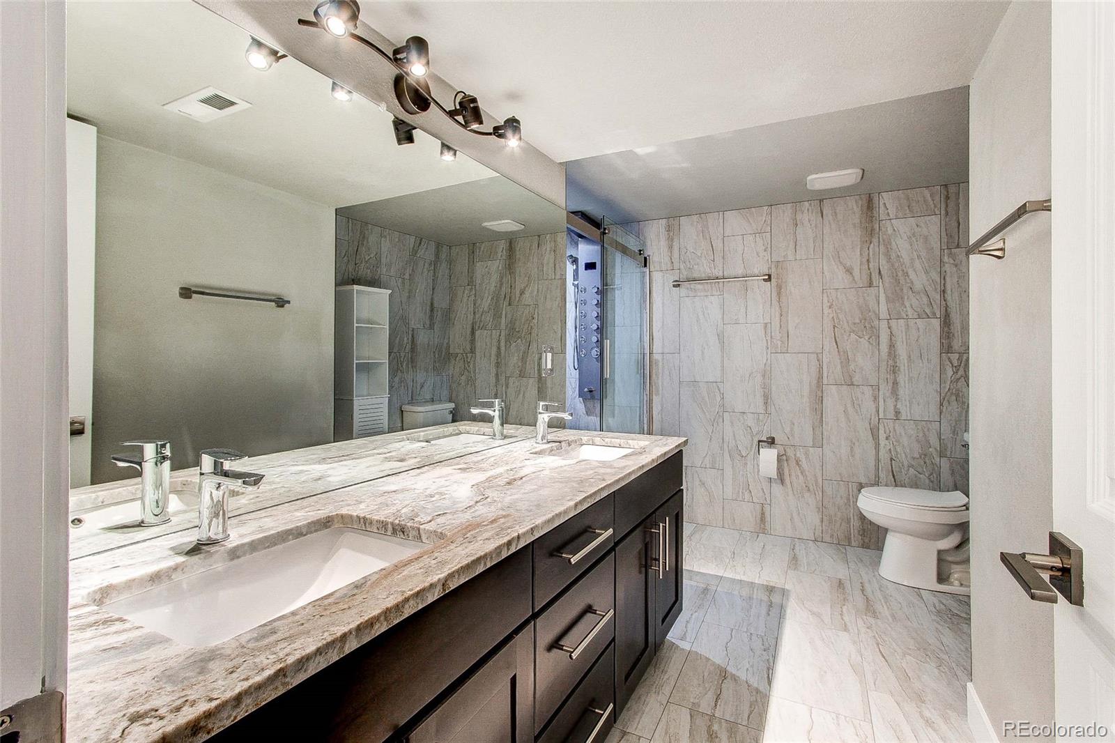 16082 Butterwort Circle Parker, CO 80134 - Photo 36 of 39 a bathroom with a granite countertop sink a toilet and shower