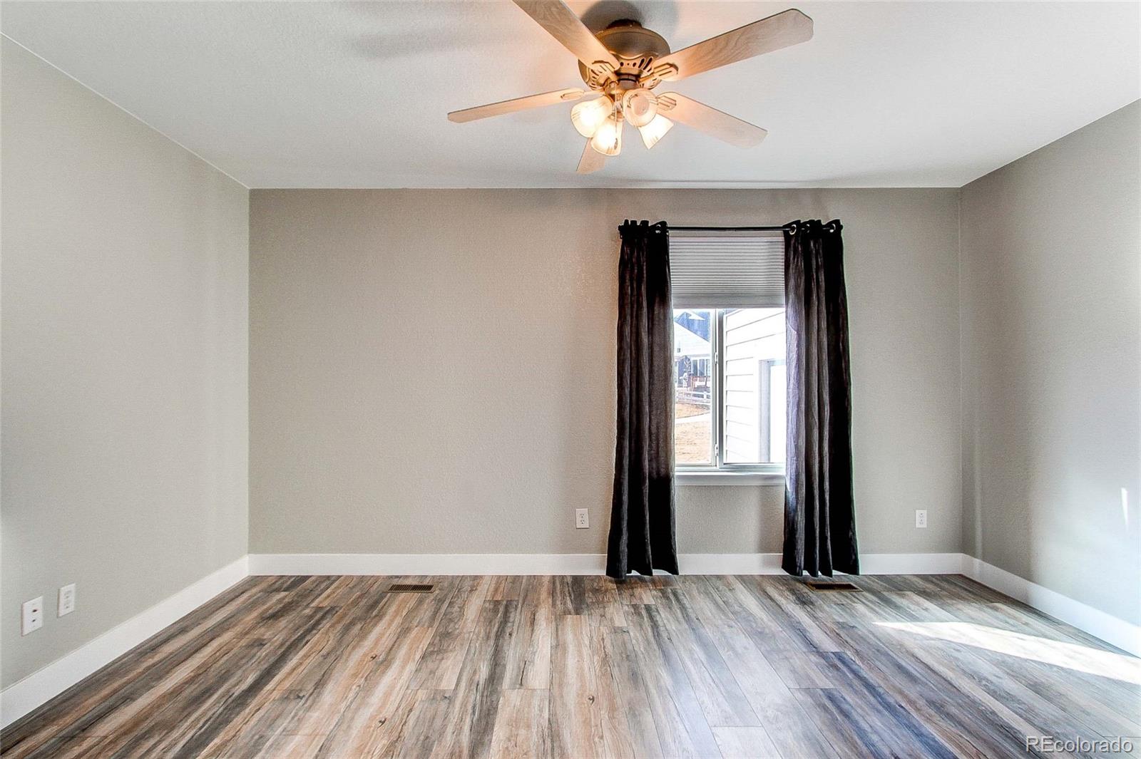 16082 Butterwort Circle Parker, CO 80134 - Photo 10 of 39 an empty room with wooden floor fan and windows