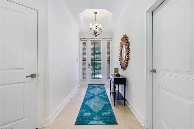 a hallway with front door wooden floor and a chandelier