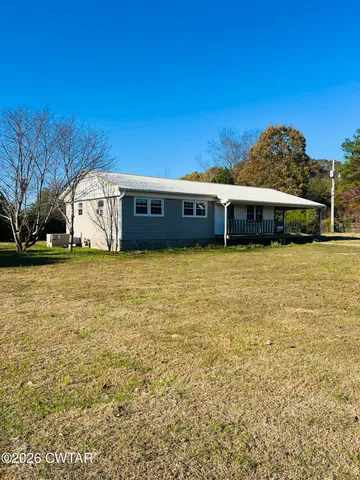 a view of a large pool with lawn chairs under an umbrella