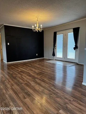 a view of a livingroom with wooden floor a chandelier and windows