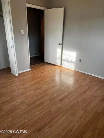 an empty room with wooden floor and entrance