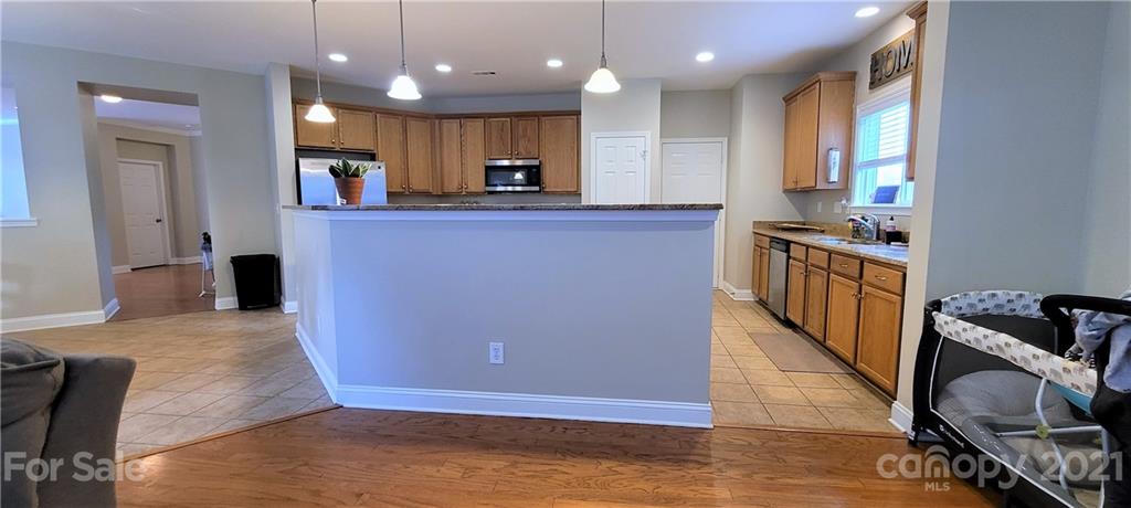 9611 Seamill Road Charlotte, NC 28278 - Photo 9 of 26 a kitchen with kitchen island granite countertop wooden cabinets and a refrigerator