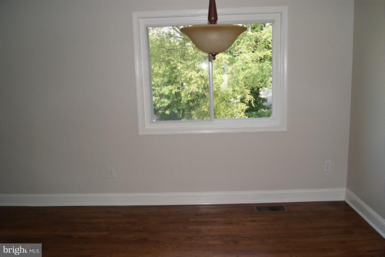 a view of empty room with wooden floor and window