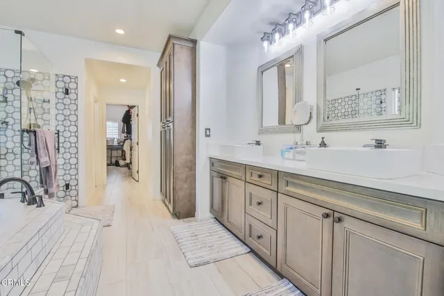 a spacious bathroom with a double vanity sink a mirror and a shower