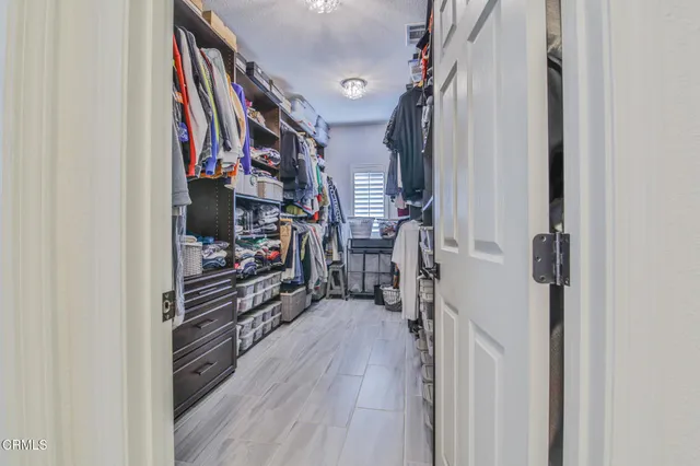 a view of walk in closet with clothes and shoes